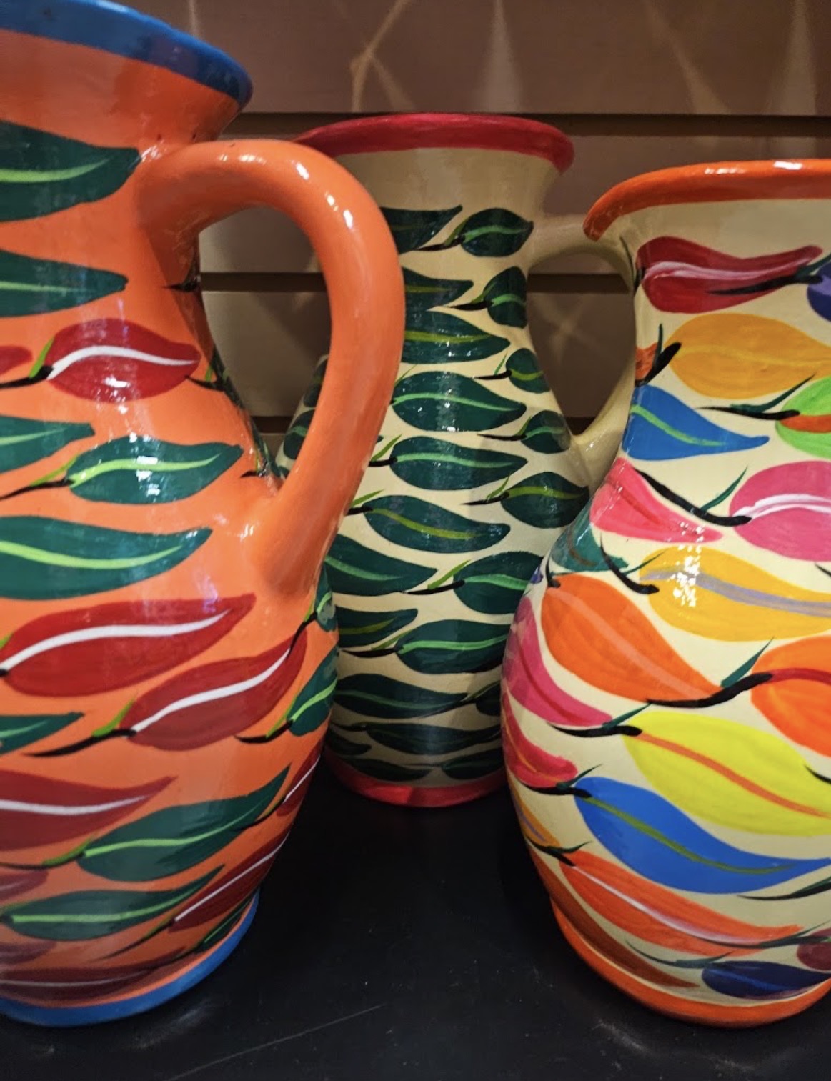 Three hand-painted ceramic pitchers with chile pepper designs