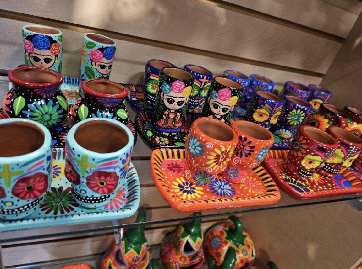 Colorful hand-painted Mexican ceramic shot glasses and trays on a shop shelf