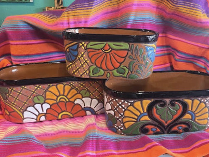 Hand-painted Talavera planters displayed on a striped serape