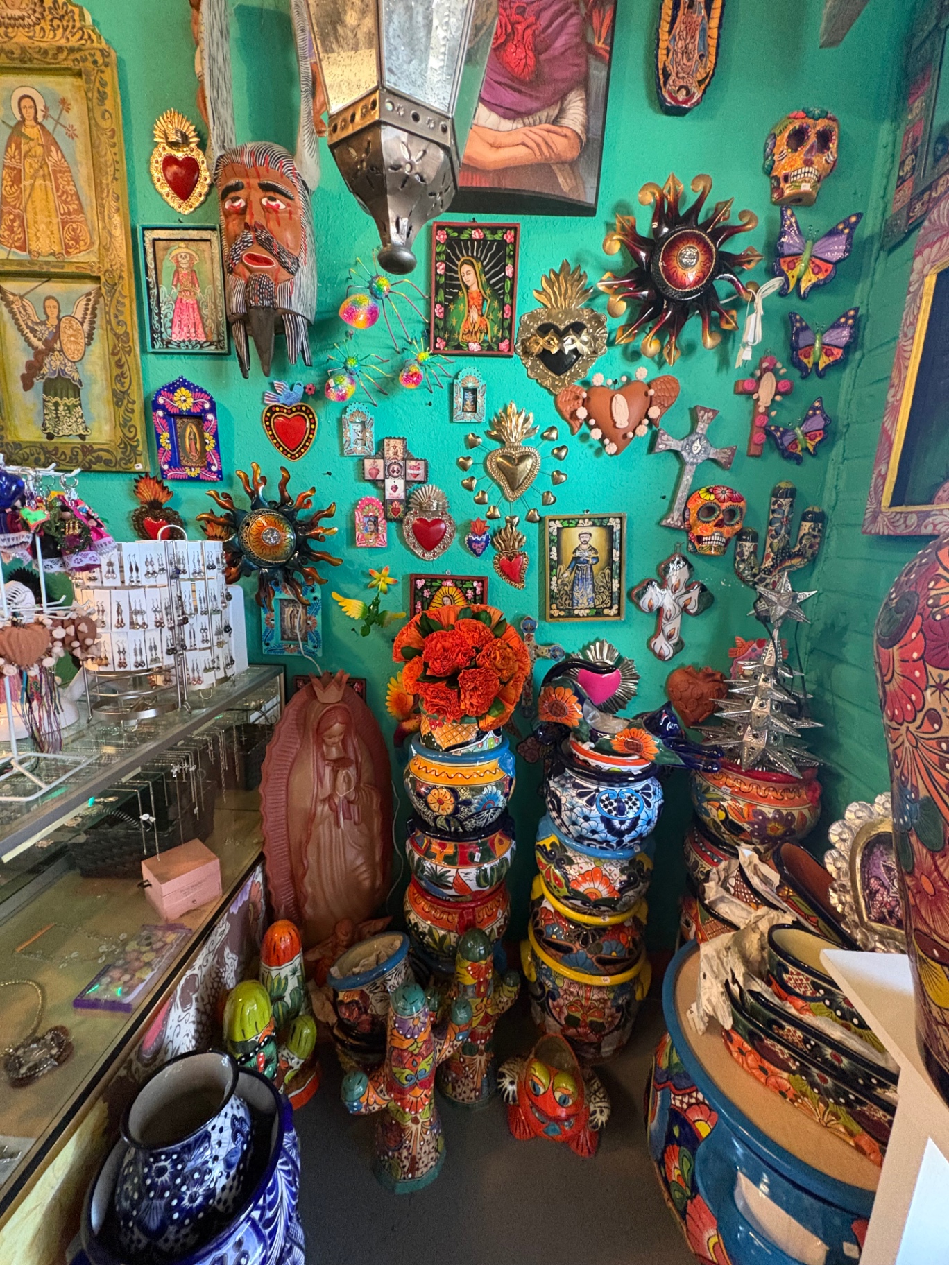 Teal wall covered with milagros, suns and Mexican devotional art